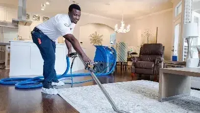 Technician running an extraction wand across a soaked rug in a living room