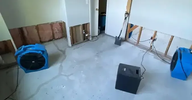 Air movers and a dehumidifier running where lower drywall was removed, representing restoration in Cerritos.