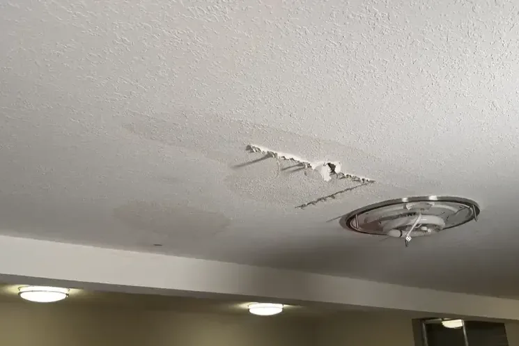 Water stain and peeling ceiling texture next to an air conditioning vent